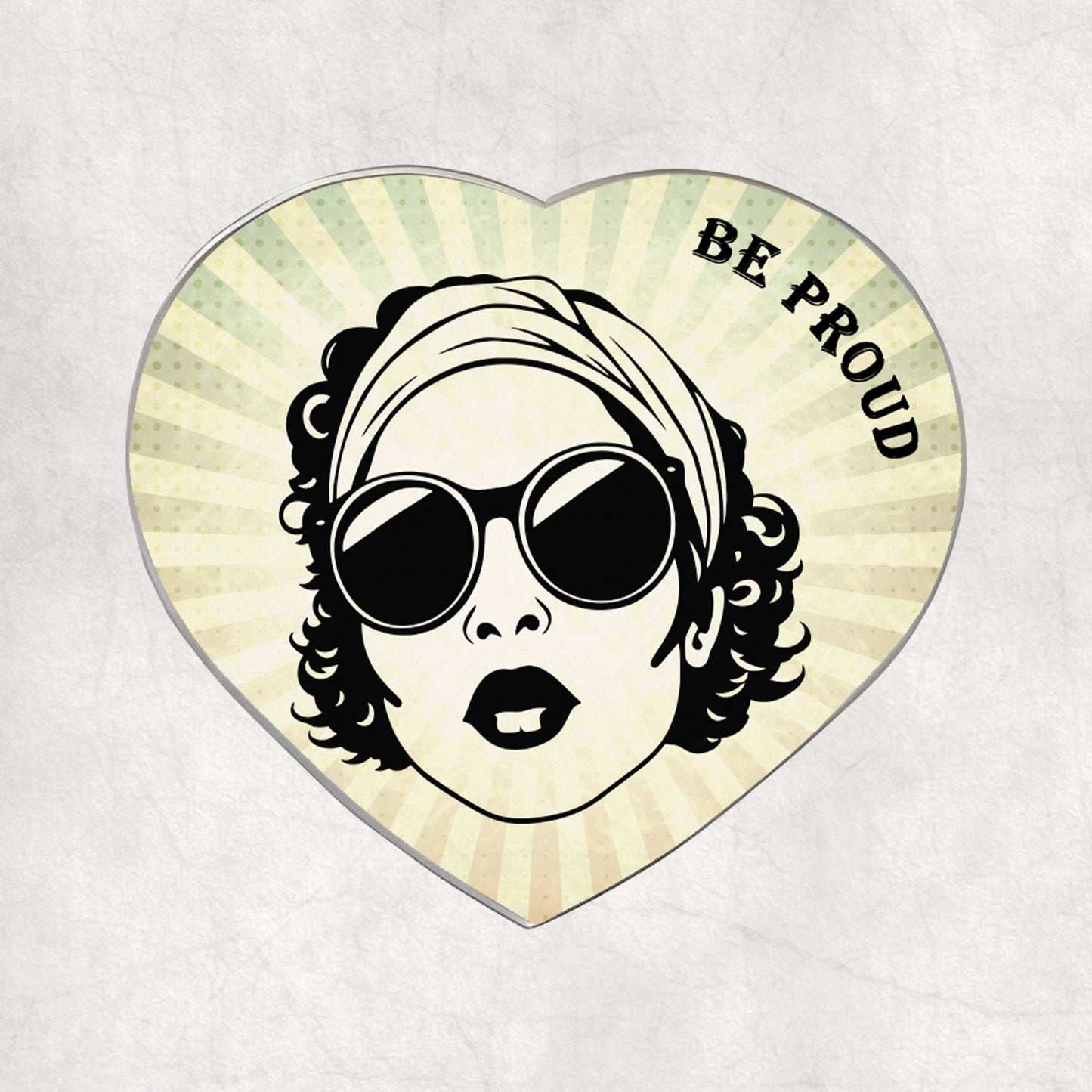Heart-shaped metal magnet with a stylised woman's face wearing sunglasses and a headscarf, with 'BE PROUD' text on a light vintage background.