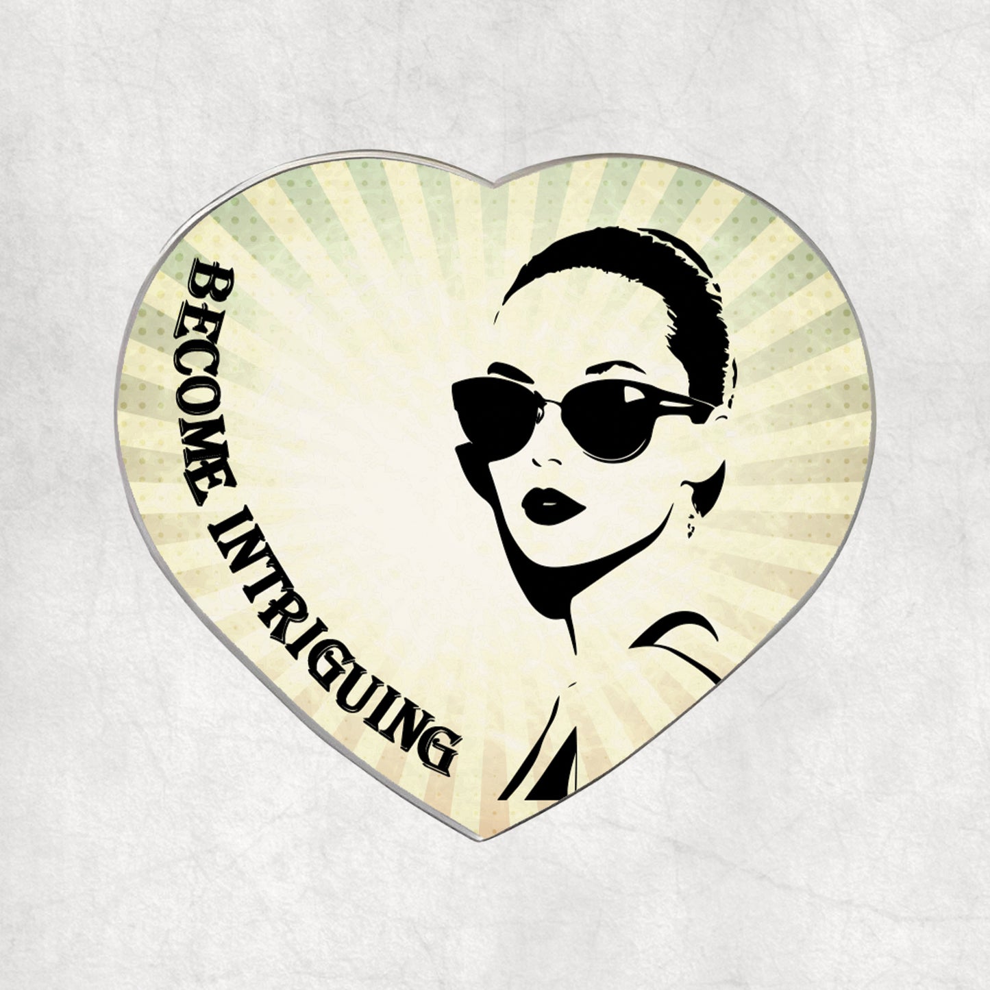 Heart-shaped metal magnet with a woman's face and 'Become Intriguing' text on a light vintage background