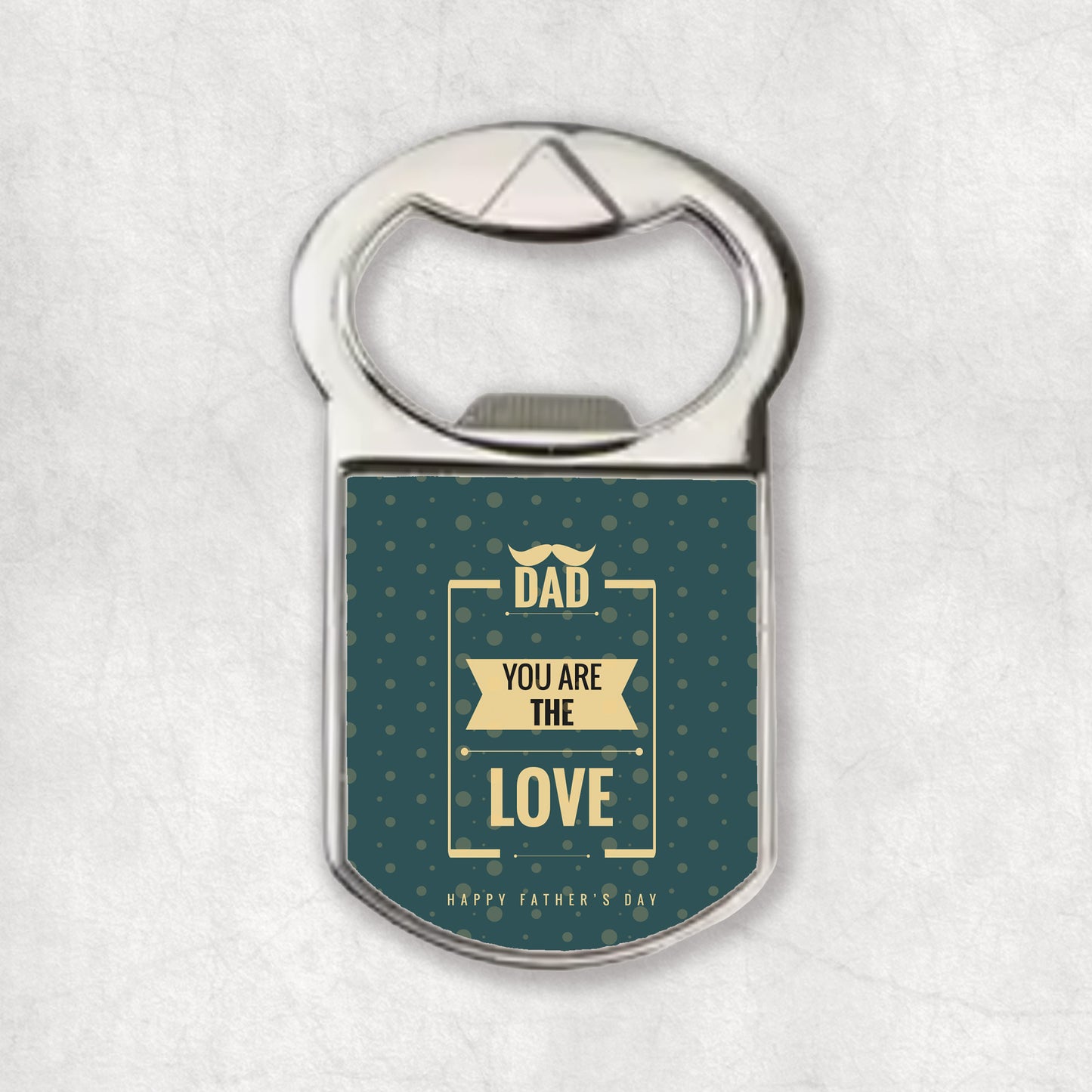 A bottle opener magnet with a greenish background and text that reads 'DAD YOU ARE THE LOVE'.