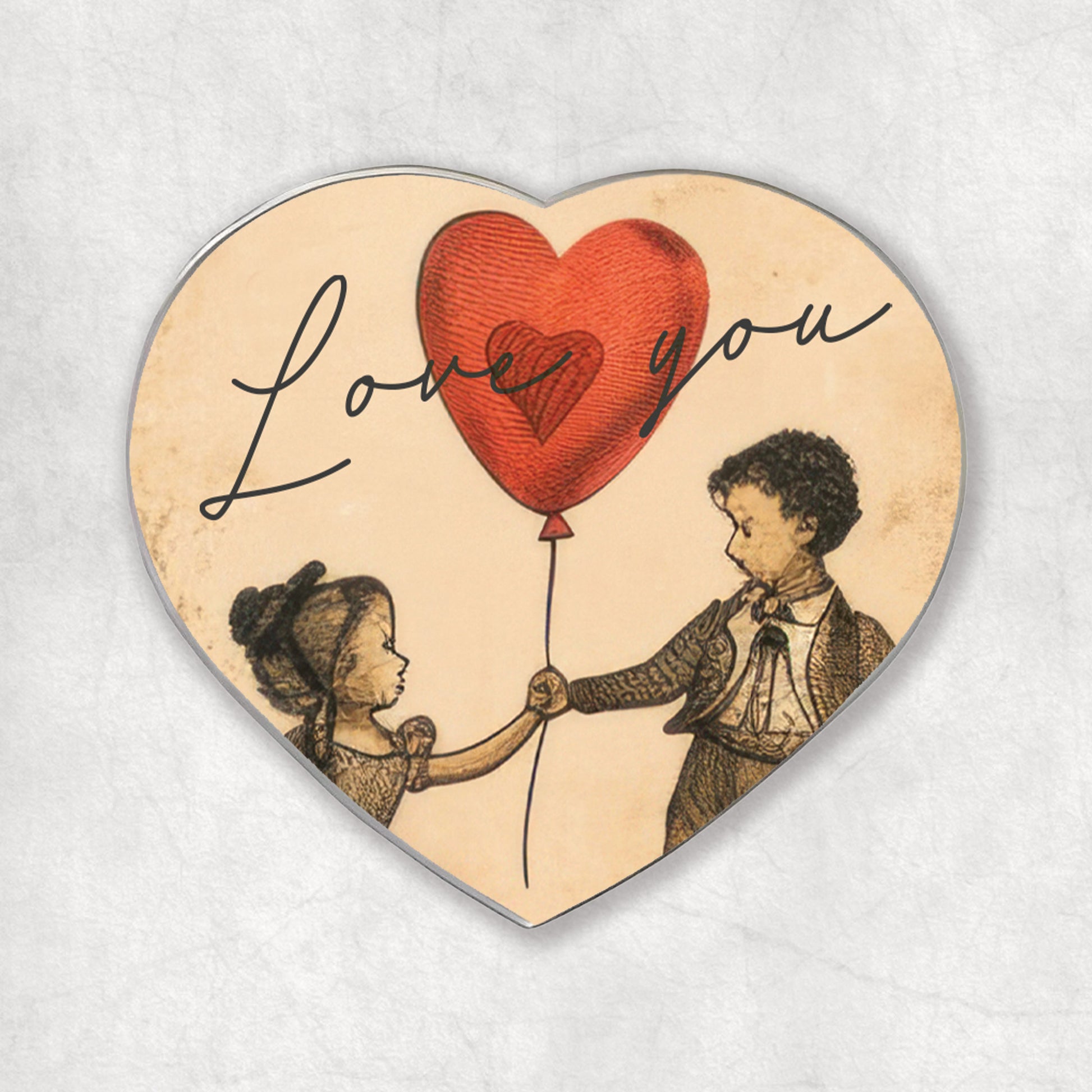 A heart-shaped magnet with an illustration of a couple and the phrase 'Love you' on it, with a red balloon in the shape of a heart.