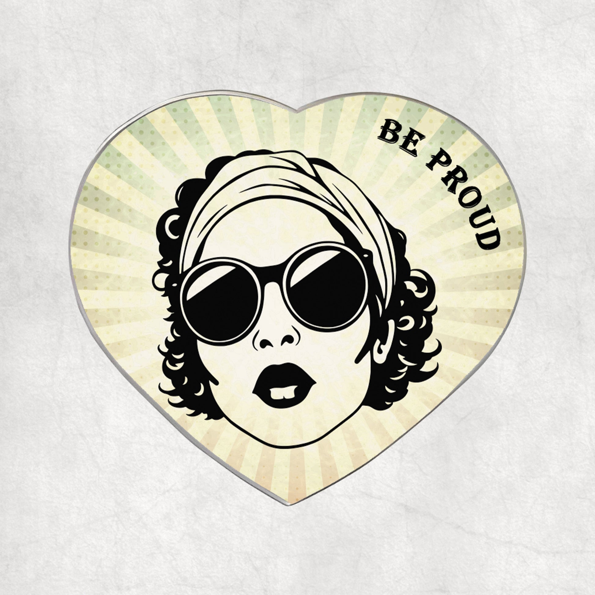 Heart-shaped metal magnet with a stylised  woman's face wearing sunglasses and a headscarf, with 'BE PROUD' text on a light vintage background.