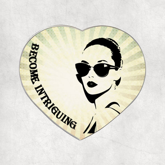 Heart-shaped metal magnet with a woman's face and 'Become Intriguing' text on a light vintage background