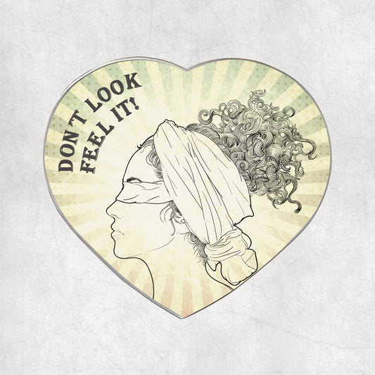 Heart-shaped metal magnet with a profile of a blindfolded woman and text 'DON'T LOOK FEEL IT!' text on a light vintage background.
