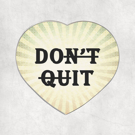 Heart-shaped metal magnet with 'DON'T QUIT' text on a light vintage background.