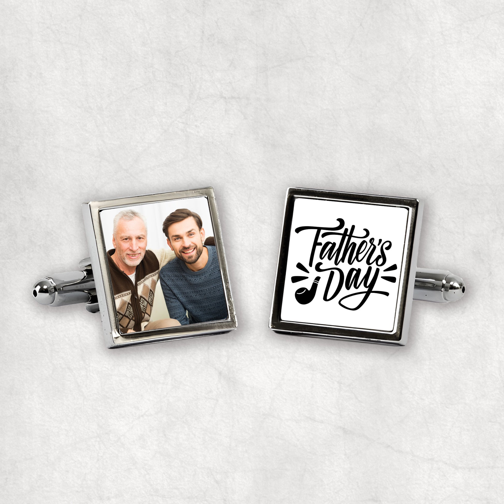 A pair of silver personalised cufflinks with one featuring a photo print and the other with 'Father's Day' text, both on a white background.