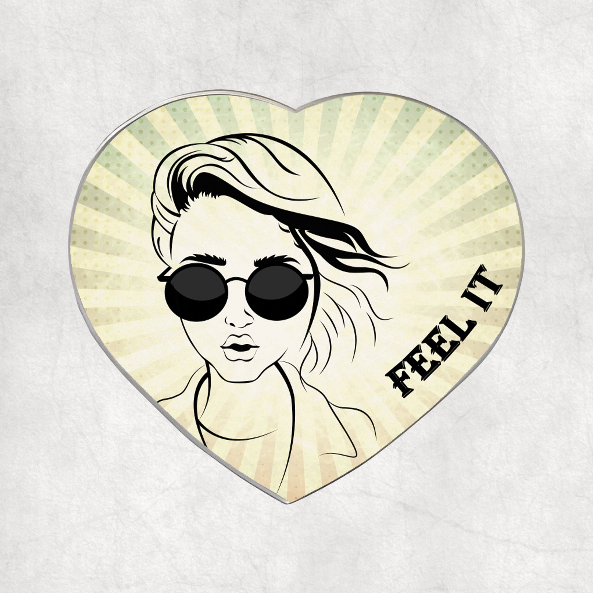 Heart-shaped metal magnet with a stylised face wearing sunglasses and 'FEEL IT' text on a light vintage background.