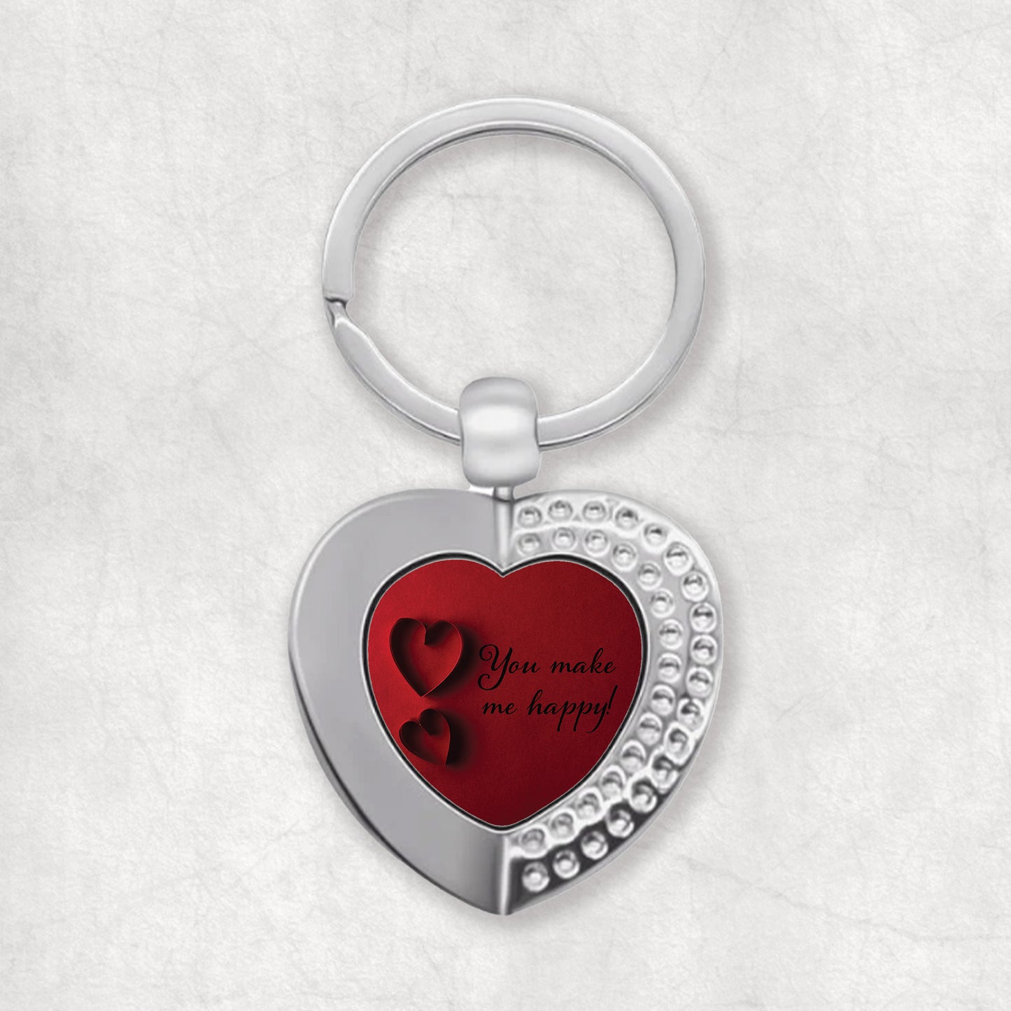 A heart-shaped keyring with a red design, featuring the text 'You make me happy'.