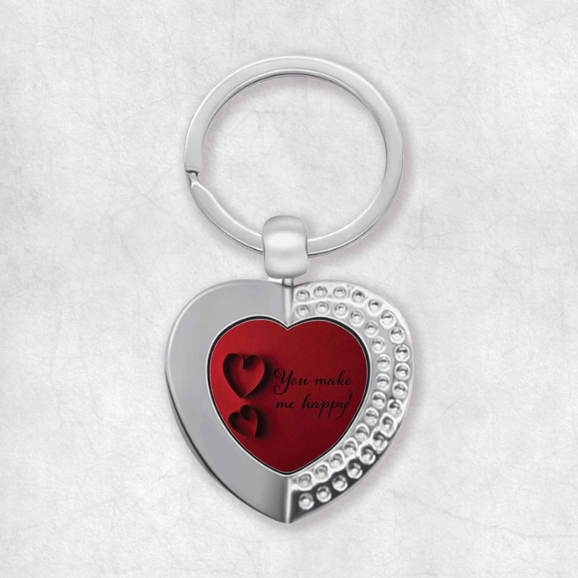 A heart-shaped keyring with a red design, featuring the text 'You make me happy'.