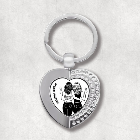 Metal heart-shaped keychain with an illustration of two women and 'Besties Forever' text written on a white background, perfect for celebrating friendship.