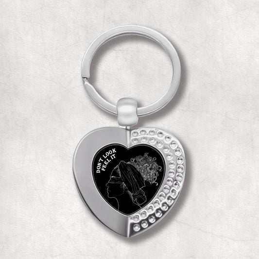 Metal heart-shaped keychain with a woman image and 'Don't Look, Feel It' text written on a black background.