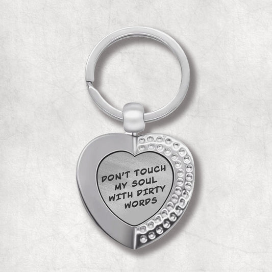 Metal heart-shaped keychain with 'Don't touch my soul with dirty words' text written on a grey patterned background.