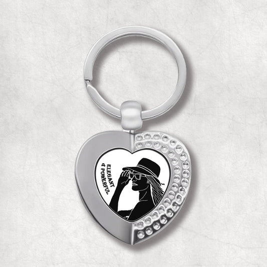 Metal heart-shaped keychain with a silhouette illustration of a woman, and text 'Elegant & Powerful' written on a white background.
