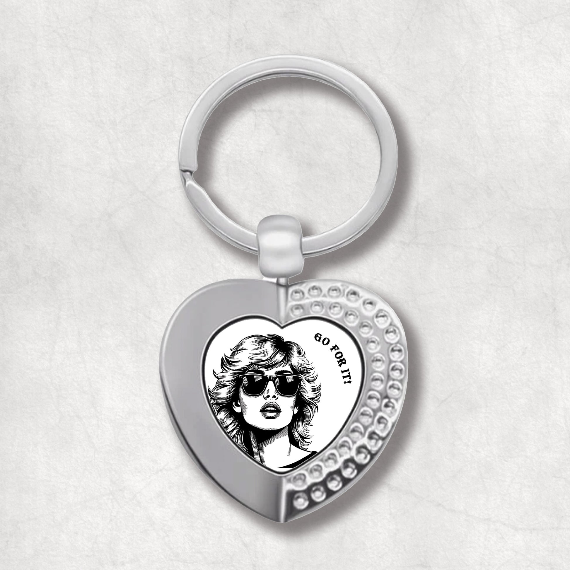 Metal heart-shaped keychain with a woman's portrait and 'go for it!' text written on a white background.